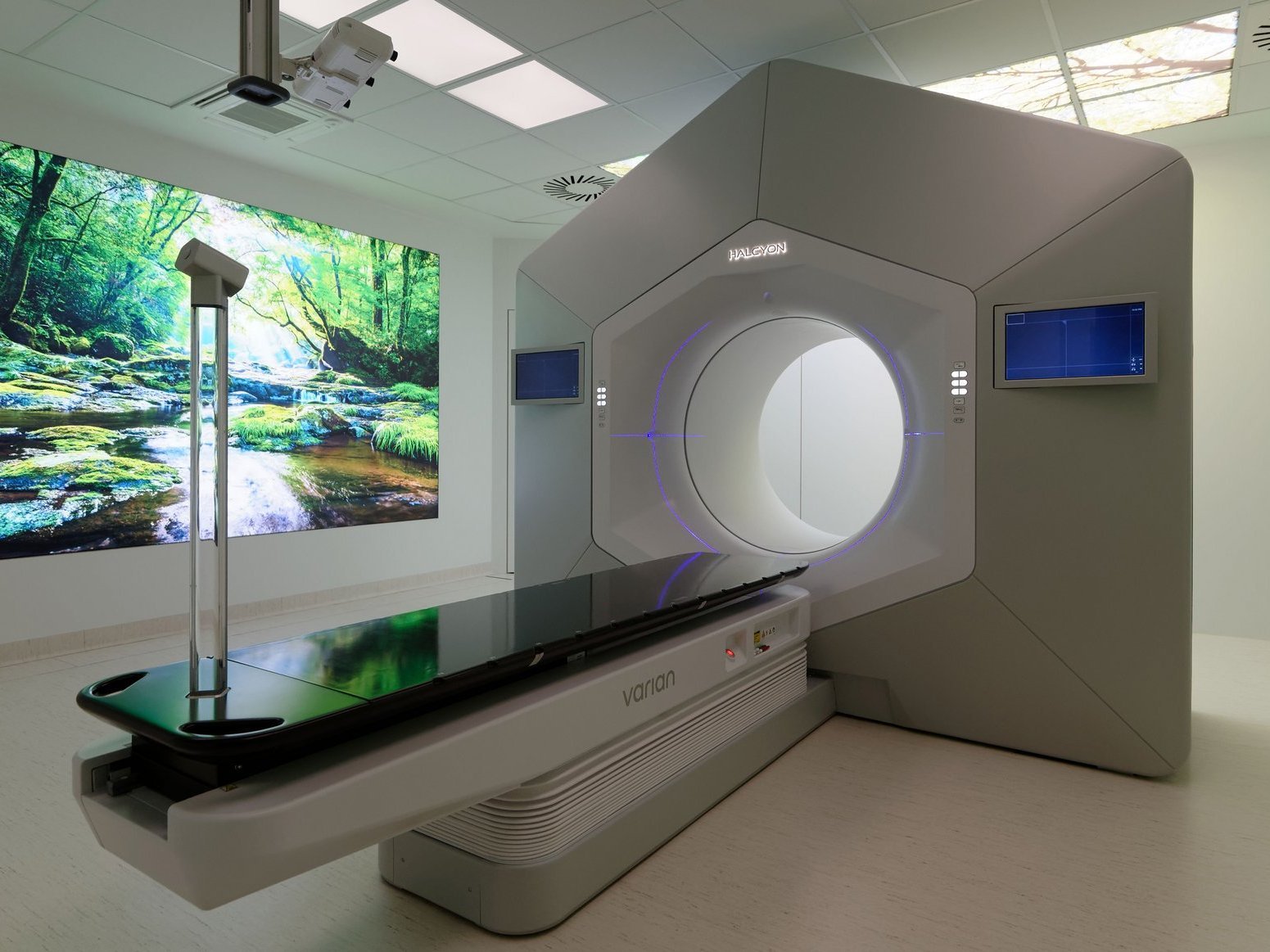 Moderner Bestrahlungsraum mit großem Therapiegerät und beruhigender Naturprojektion an der Wand