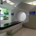 Moderner Bestrahlungsraum mit großem Therapiegerät und beruhigender Naturprojektion an der Wand