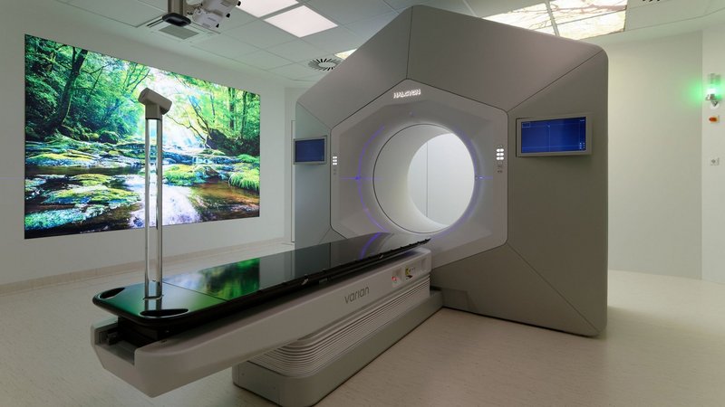 Moderner Bestrahlungsraum mit großem Therapiegerät und beruhigender Naturprojektion an der Wand